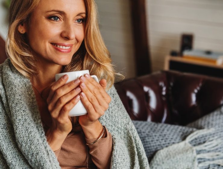 Woman drinking coffee wrapped in a blanket