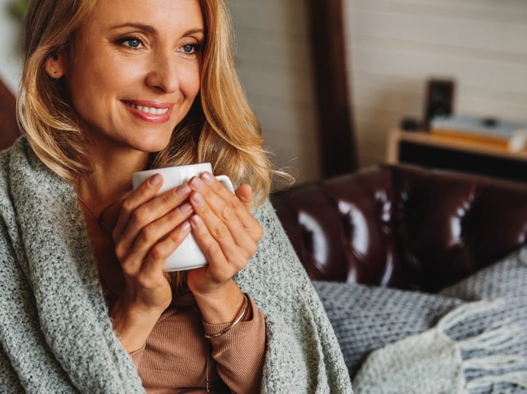 Woman drinking coffee wrapped in a blanket