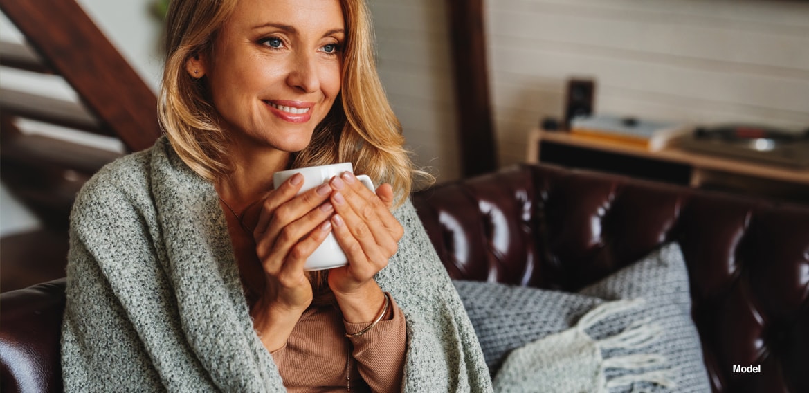 Woman drinking coffee wrapped in a blanket