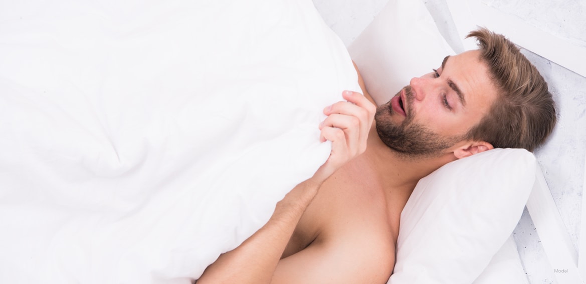 Man laying in bed looking at himself