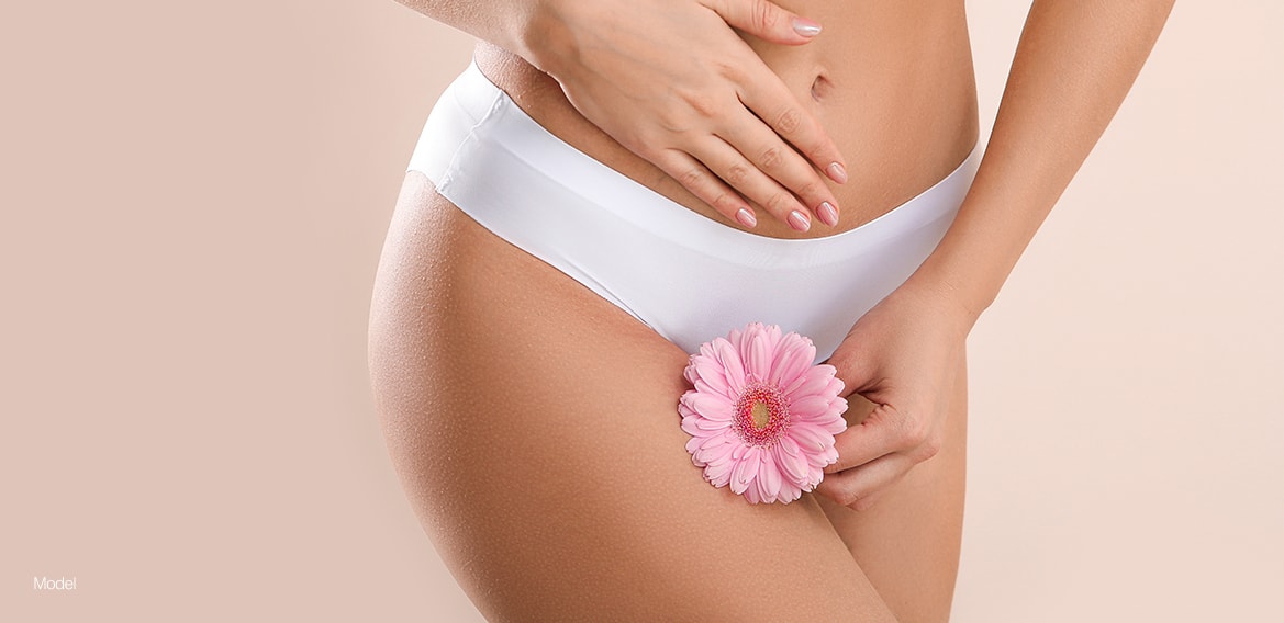 Women in underwear holding a flower against her thigh.