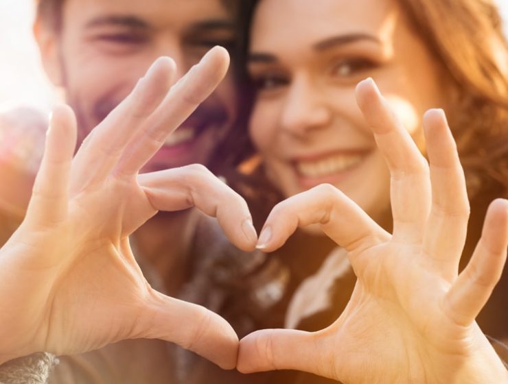 A happy couple making a heart shape with their hands.