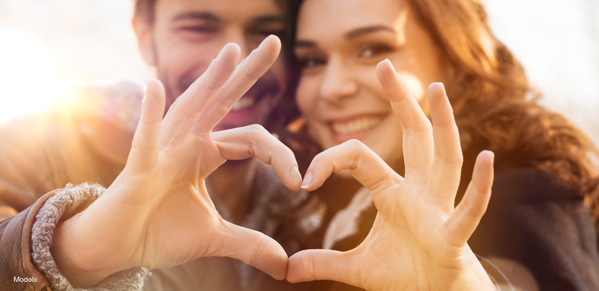 A happy couple making a heart shape with their hands.