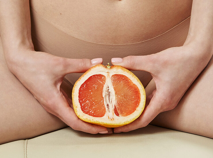 Female holding grapefruit in front of her